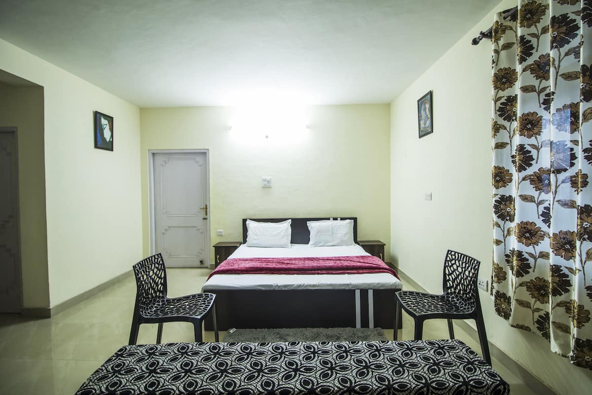 A bedroom with a bed, two chairs, a bench, a door, and a curtain.