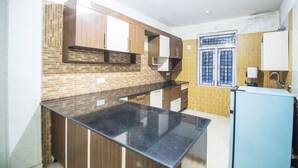 A kitchen with wooden cabinets, a black countertop, and a blue refrigerator. - Comfort Homestay (Dalhousie)
