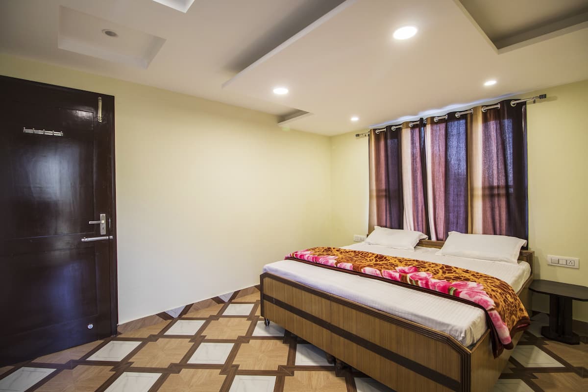 A bedroom with a bed, curtains, a door, and a tiled floor.