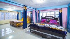 A bedroom with a large bed, a smaller bed, and a desk. - Comfort Homestay (Dalhousie)