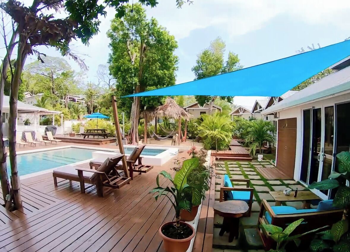 A pool area with lounge chairs, a table, and potted plants.