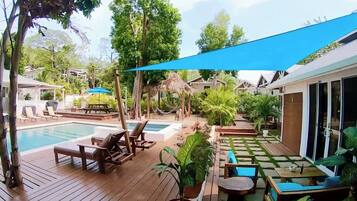 A pool area with lounge chairs, a table, and potted plants.