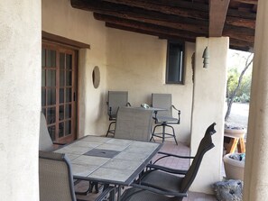 A patio area with a table and four chairs, a wooden door, and a window. - Authentic Adobe Retreat at the No Way Dude Ranch (Tucson)