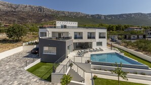 Une maison moderne à deux étages, dotée d’une piscine, d’un patio couvert et offrant une vue sur les montagnes.