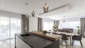 Une cuisine moderne dotée d’un îlot central, d’un coin repas avec des chaises et d’un éclairage suspendu.