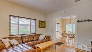 A living room with a brown leather sofa, a wooden coffee table, and a dining area with a wooden table and chairs. - 3BR Hot-tub & Dog-friendly Old Colorado City!! (Colorado Springs)