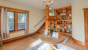 A library with wooden bookshelves, a chandelier, and a staircase.