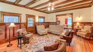 A spacious living room with wooden beams, a large sofa, armchairs, and a patterned rug.