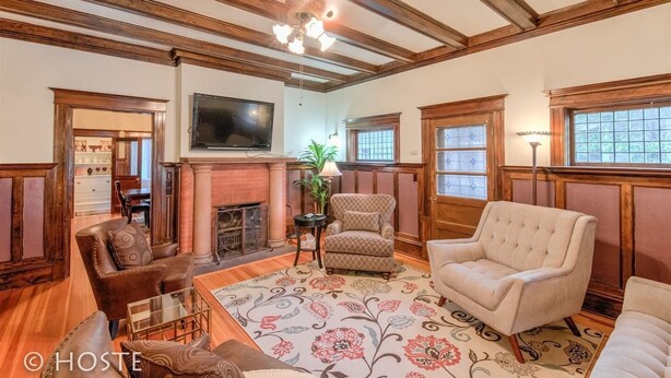 A spacious living room with wooden beams, a fireplace, a television, and comfortable seating.