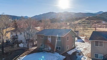 Un barrio residencial con casas, cielo despejado y montañas al fondo.