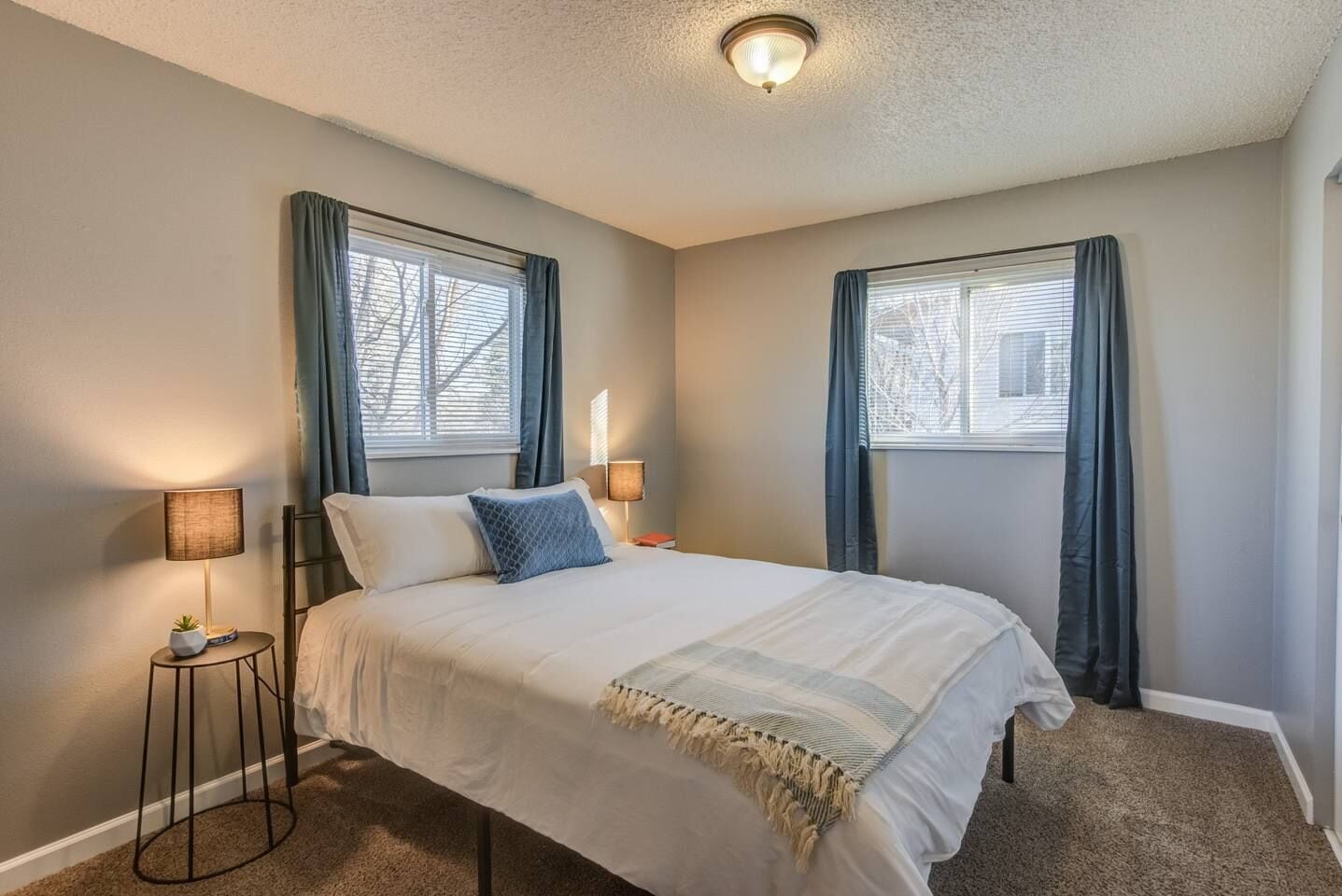 A bedroom with a bed, two bedside lamps, and a ceiling light.