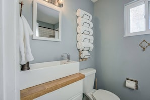 A bathroom with a white sink, a mirror, a toilet, and a towel rack with multiple towels. - 2BR Aptmt Parks Private Deck, Mountain Views! (Colorado Springs)