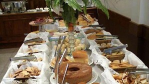 Una mesa de buffet con diversos productos horneados y pastelería, incluyendo rosquillas, panes y bollos.