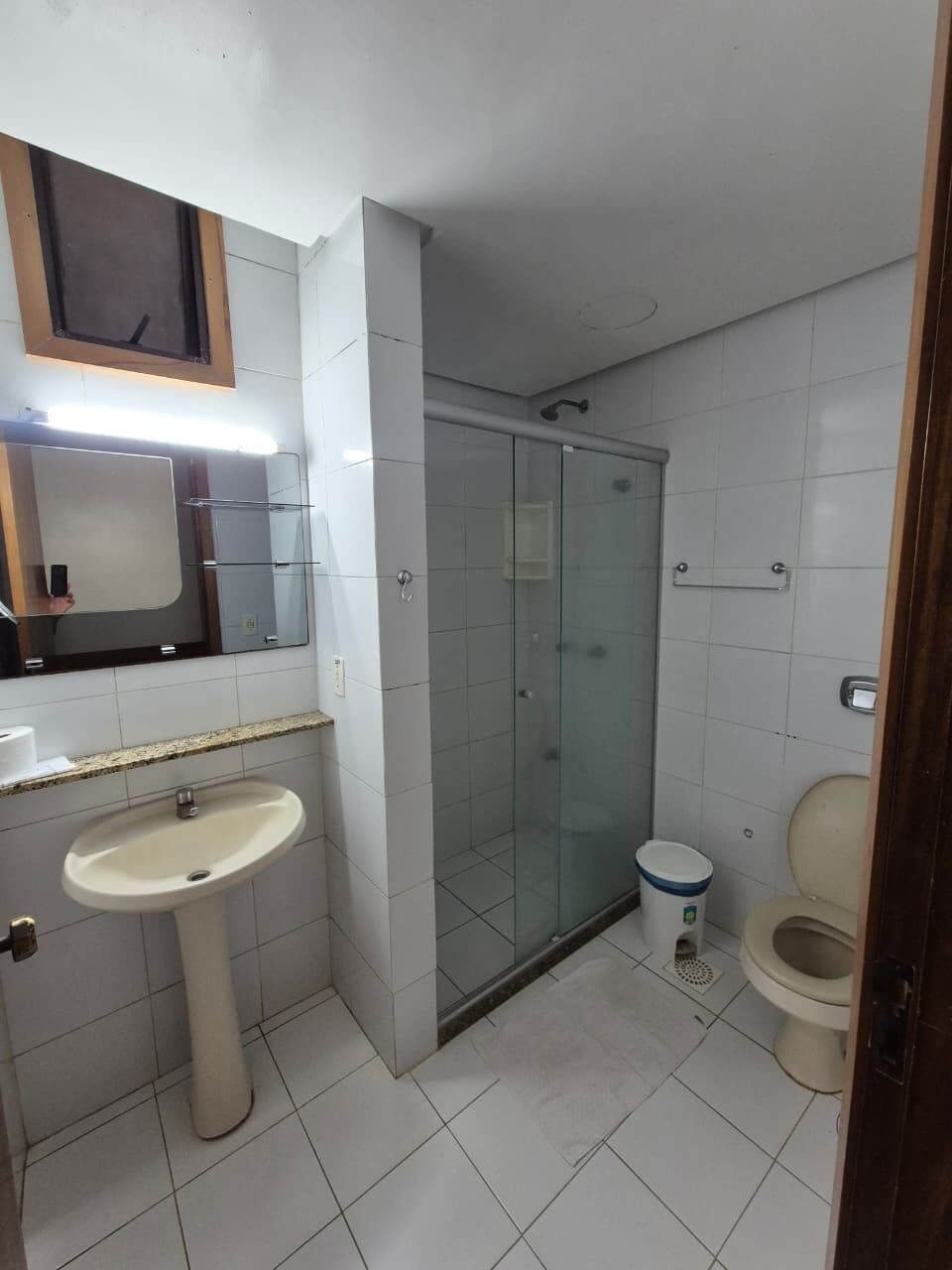 Um banheiro com pia, vaso sanitário e chuveiro com box de vidro.
