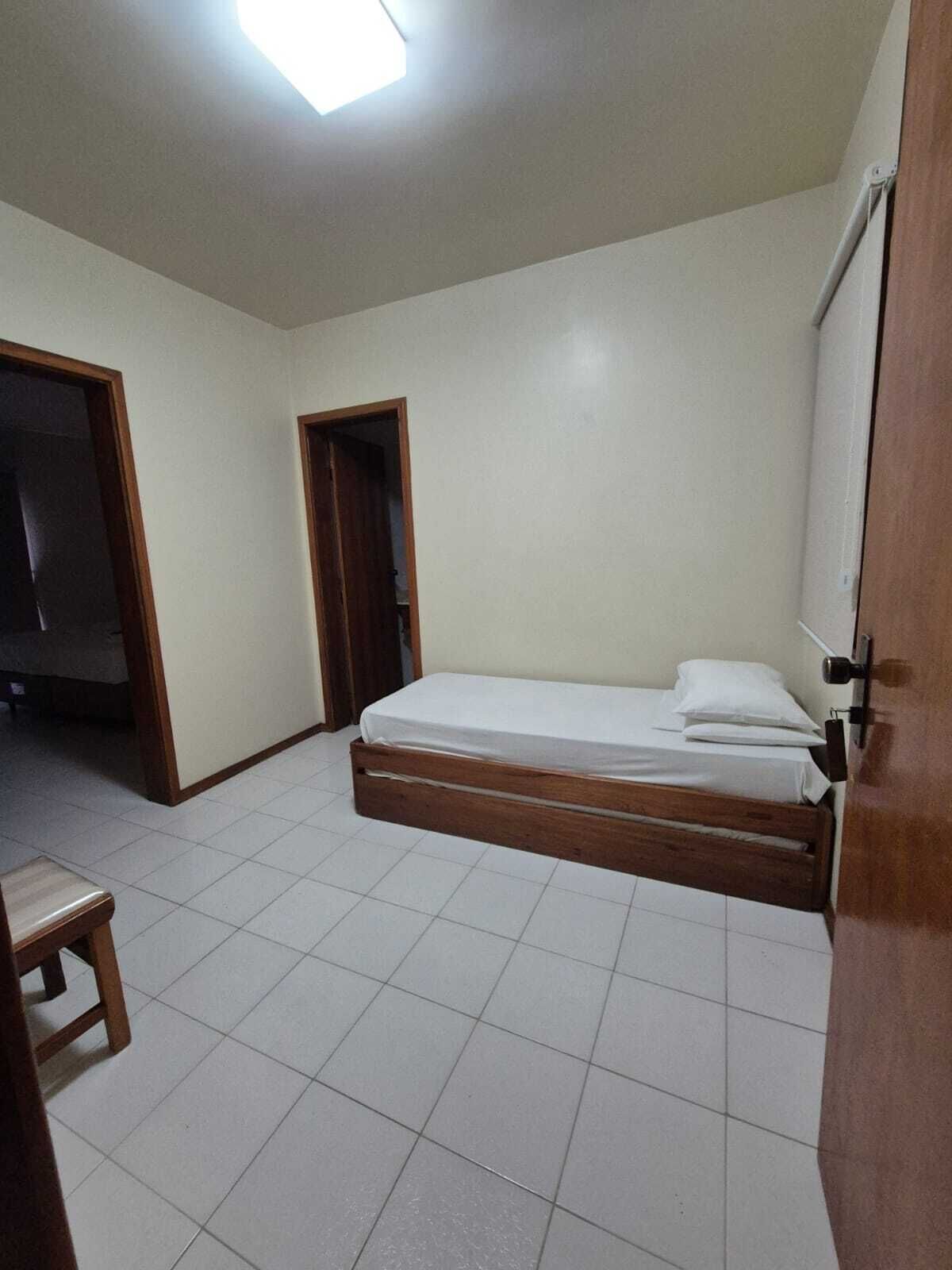 A bedroom with a single bed, a wooden door, and a tiled floor.