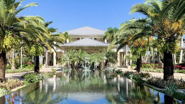 A pool with palm trees and a building in the background. - Luxurious Four Seasons PR Bahia Beach Villa; Golf, Pool, Tennis & Golf Cart (Río Grande)