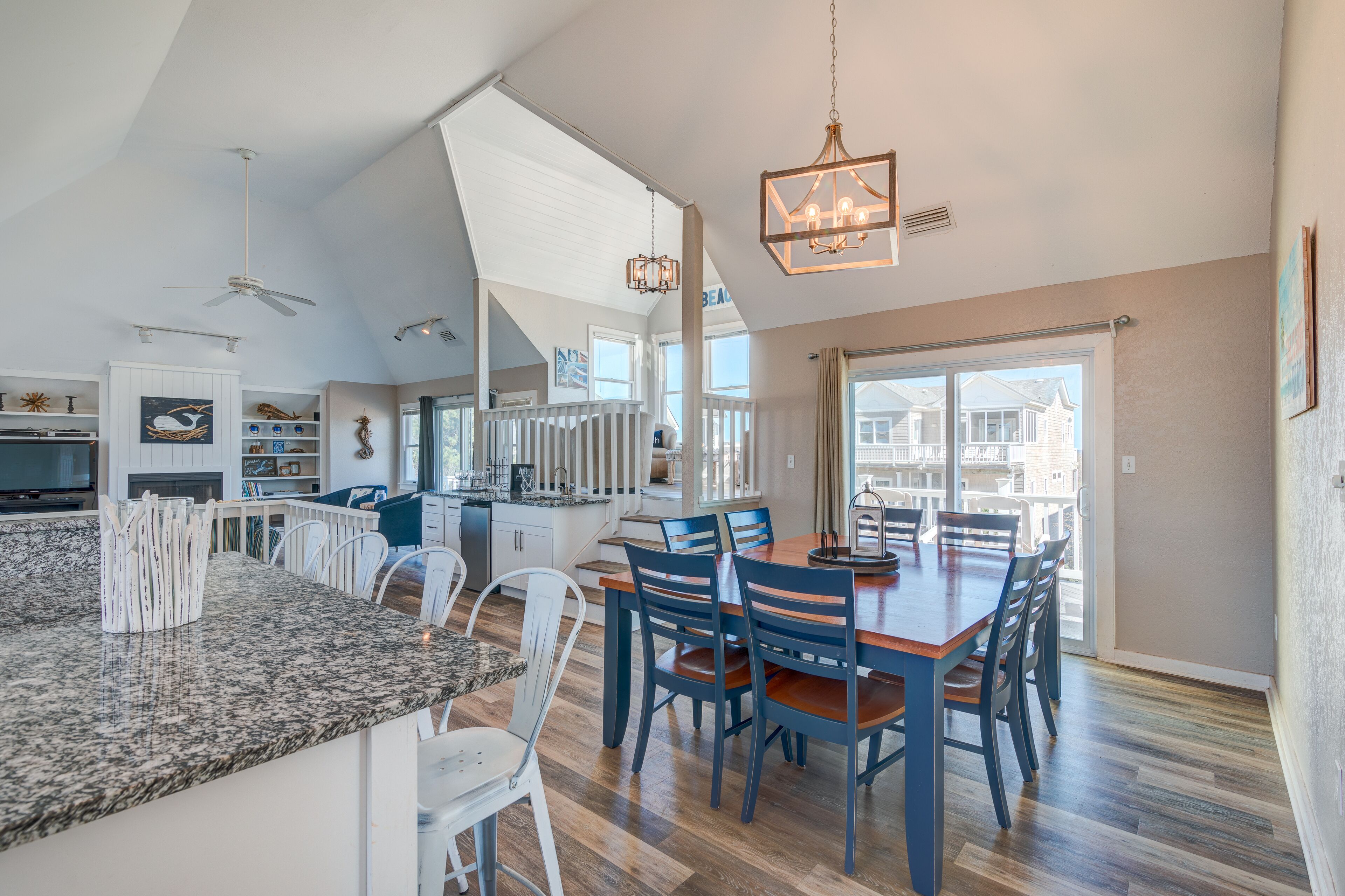 A spacious kitchen with a granite countertop, white cabinetry, and a dining area with a wooden table and blue chairs.