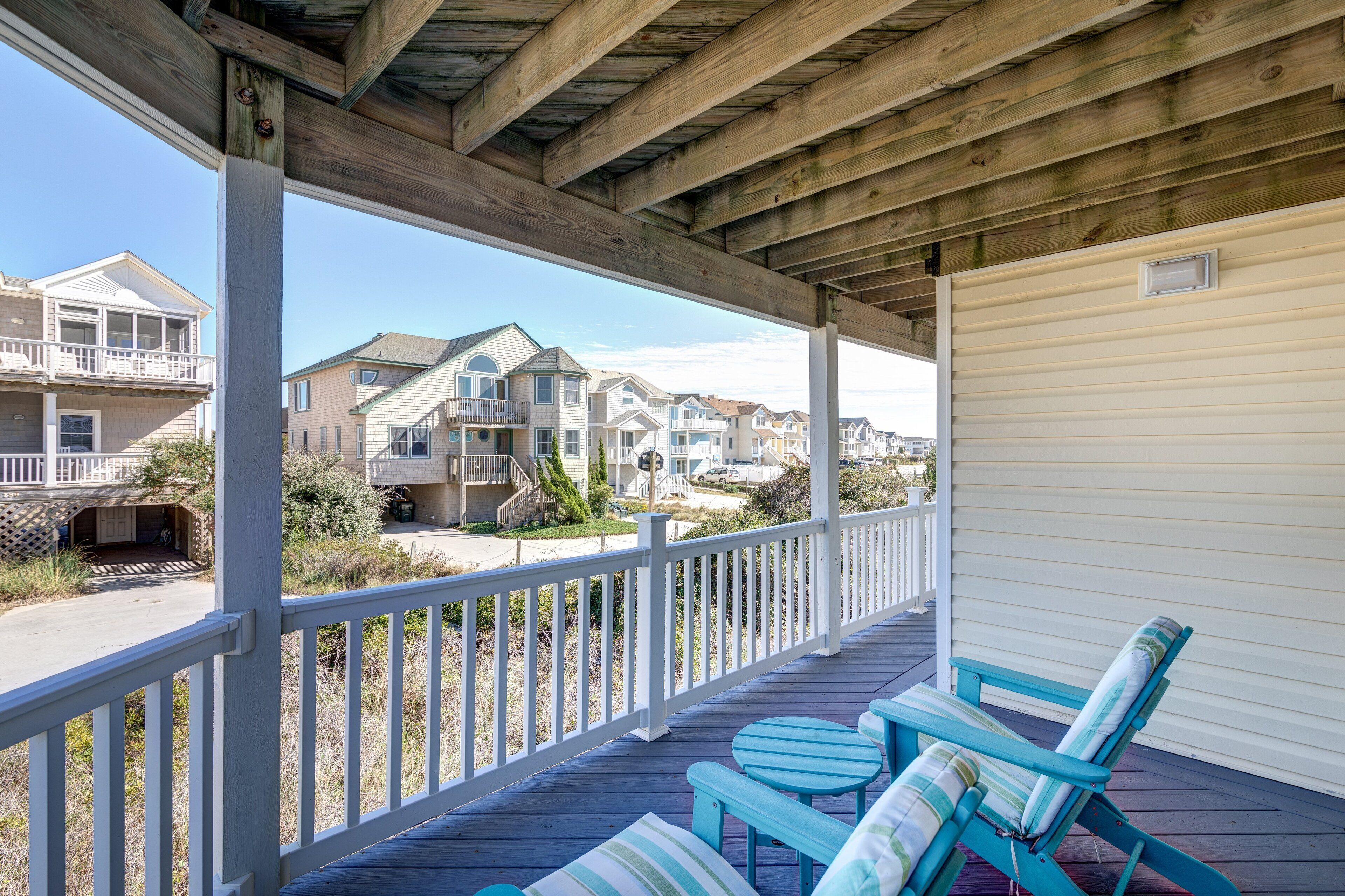 A covered porch with blue chairs and a view of neighboring houses.