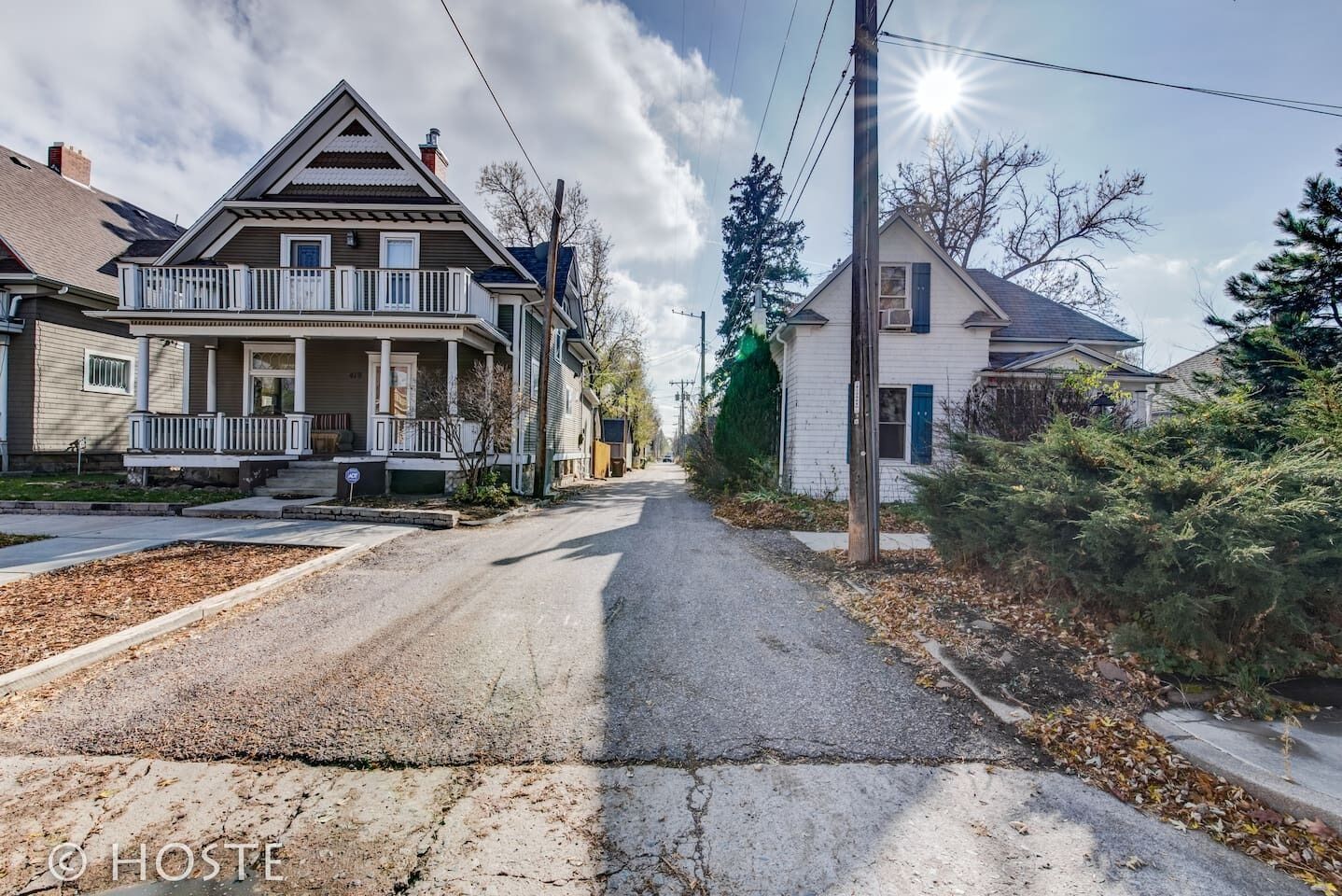 Une rue résidentielle bordée de maisons, avec une allée et un poteau électrique.