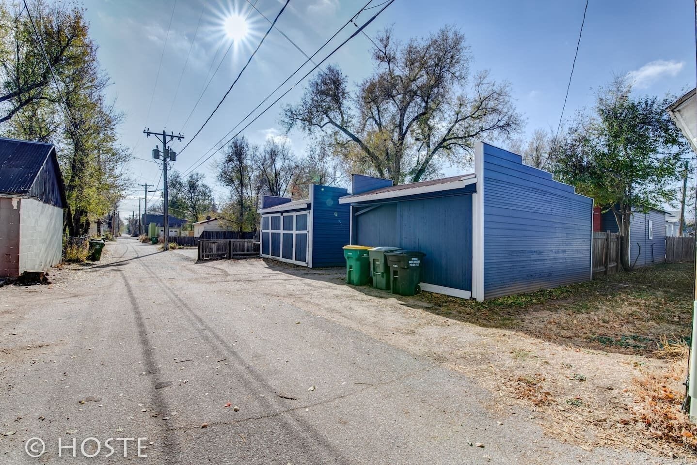 Une rue résidentielle bordée de maisons, avec un garage, et un ciel dégagé.