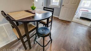 A dining area with a round table, two chairs, a woven placemat, and a potted plant. - City Center Cottage Netflix, Mtns & Adventure! (Colorado Springs)