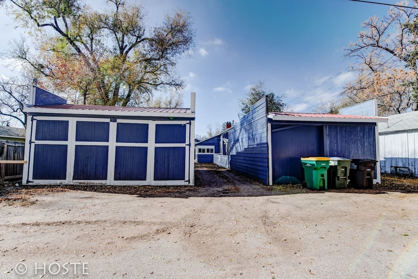 A row of blue mobile homes with a dirt ground in front.