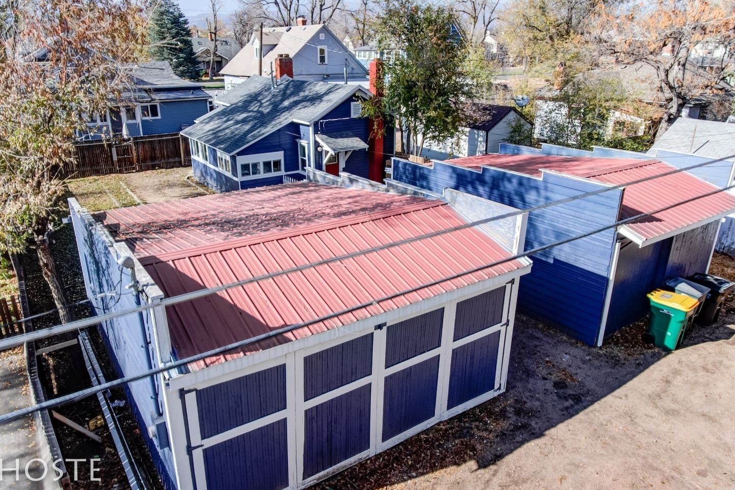 Ein Wohngebiet mit mehreren Häusern, darunter ein markantes Haus in Blau mit rotem Dach und Garage.