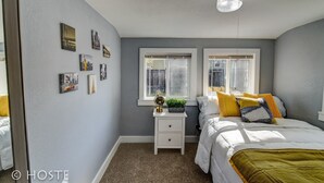 A bedroom with two beds, a nightstand, a globe, and framed pictures on the wall. - City Center Cottage Netflix, Mtns & Adventure! (Colorado Springs)