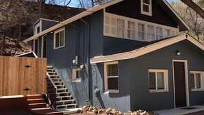 Une maison à deux étages, à l’extérieur sombre, avec un escalier en bois et une cour clôturée.