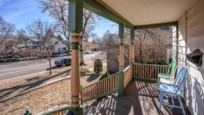 A covered porch with a view of a street and houses. - Downtown 1900 Classic 3 Bedroom Value (Colorado Springs)