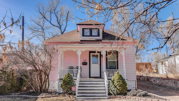 A pink single-story house with a front porch, a small front yard, and a mailbox. - Downtown 1900 Classic 3 Bedroom Value (Colorado Springs)