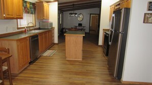 A kitchen with wooden cabinets, a central island, stainless steel appliances, and a wooden floor. - Welcome to theThe Deer Drop Inn (Hulbert)