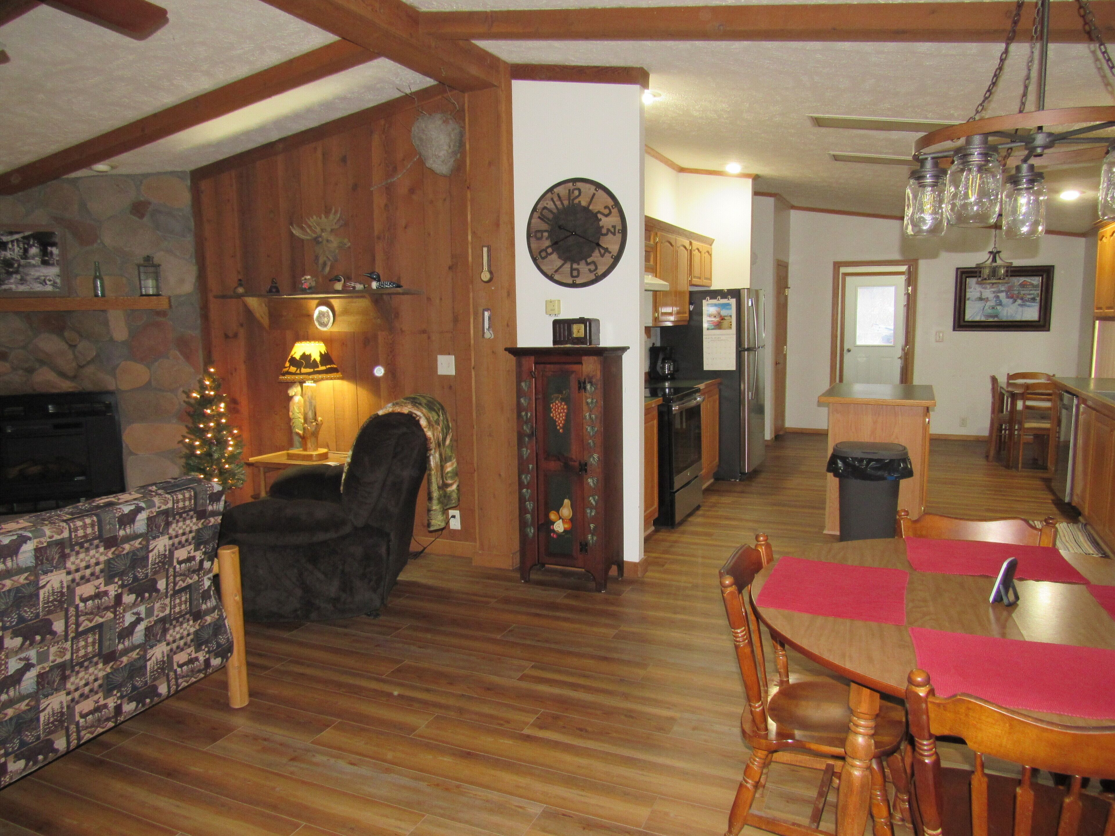 A cozy living room with a fireplace, a dining area with a wooden table and chairs, and a kitchen with wooden cabinets and appliances.