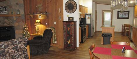 A cozy living room with a fireplace, a dining area with a wooden table and chairs, and a kitchen with wooden cabinets and appliances.