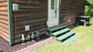 A rustic log cabin with a green door, a small porch, and a picnic table. - Welcome to theThe Deer Drop Inn (Hulbert)