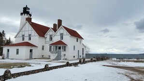 A white building with a red roof and a lighthouse tower, located near a body of water. - Welcome to theThe Deer Drop Inn (Hulbert)