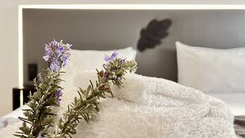 Una cama impecablemente tendida con un edredón blanco y esponjoso y una ramita de lavanda.