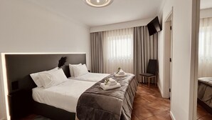 A hotel room with a large bed, a flat-screen TV, a chair, and a view of the city. - BHDouro (Baiao)