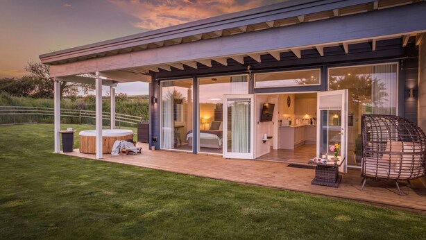 Une maison moderne dotée d’un patio couvert, d’un jacuzzi et d’une pelouse bien entretenue.