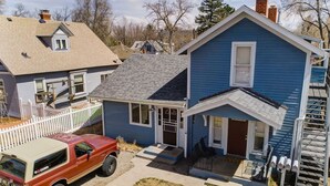 A residential area with two houses, one with a blue exterior and a front porch, and a red truck parked in front.