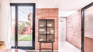 Una habitación moderna con un vidrio que da a un jardín, una estantería metálica y una pared de madera.