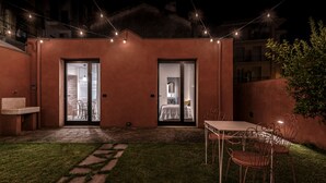 Un pequeño y acogedor patio al aire libre con una mesa, sillas, un banco y un lavamanos.