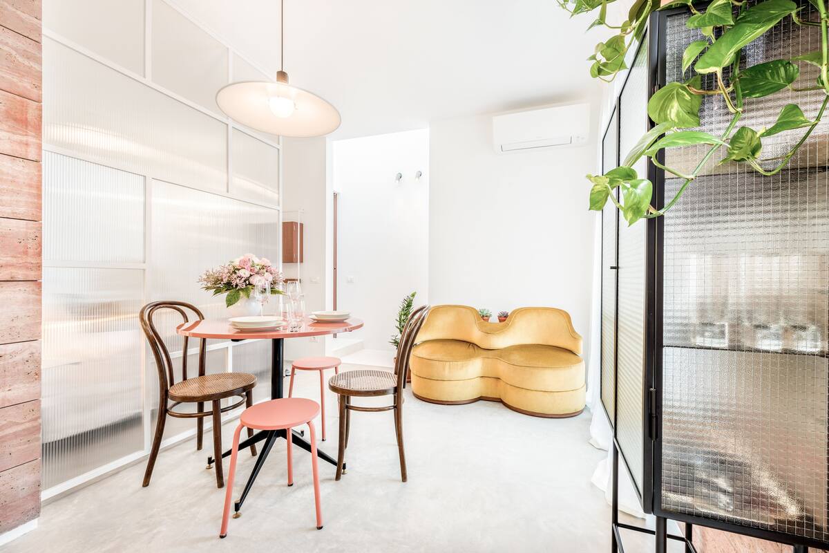 Ein modernes Interieur mit einem runden Tisch, Stühlen, einer Couch und einer hängenden Pflanze.