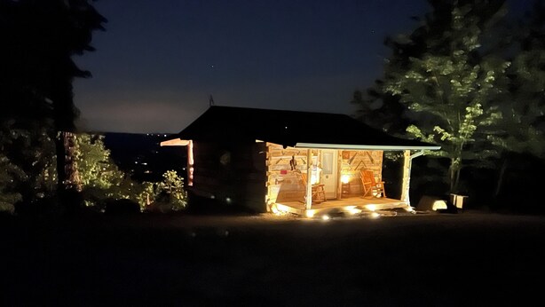 A small, illuminated cabin with a porch and a single visible door.