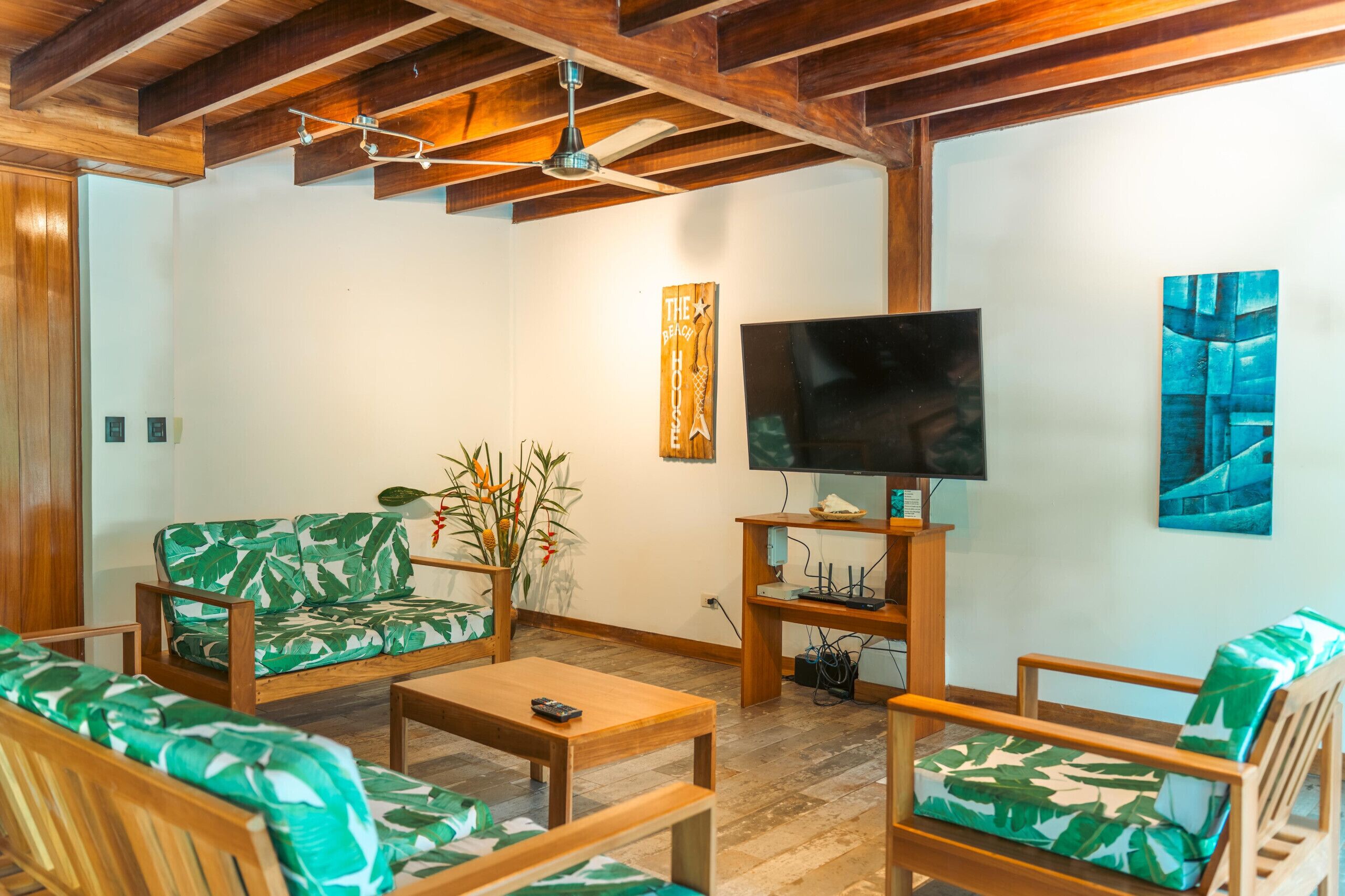 A living room with wooden furniture, a flat-screen TV, and a ceiling fan.