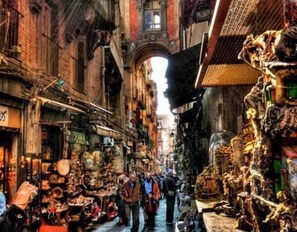 A narrow street with shops on both sides, featuring various items for sale. - Dante Rooms (Naples)