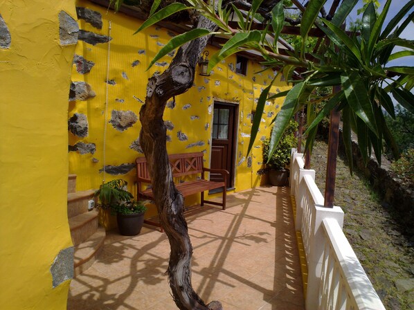 Un bâtiment jaune avec un banc en bois et des plantes en pot.