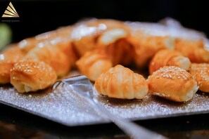 Ett fat med gyllenbruna bakverk, troligen croissanter, täckta med sesamfrön, placerade på en reflekterande yta.