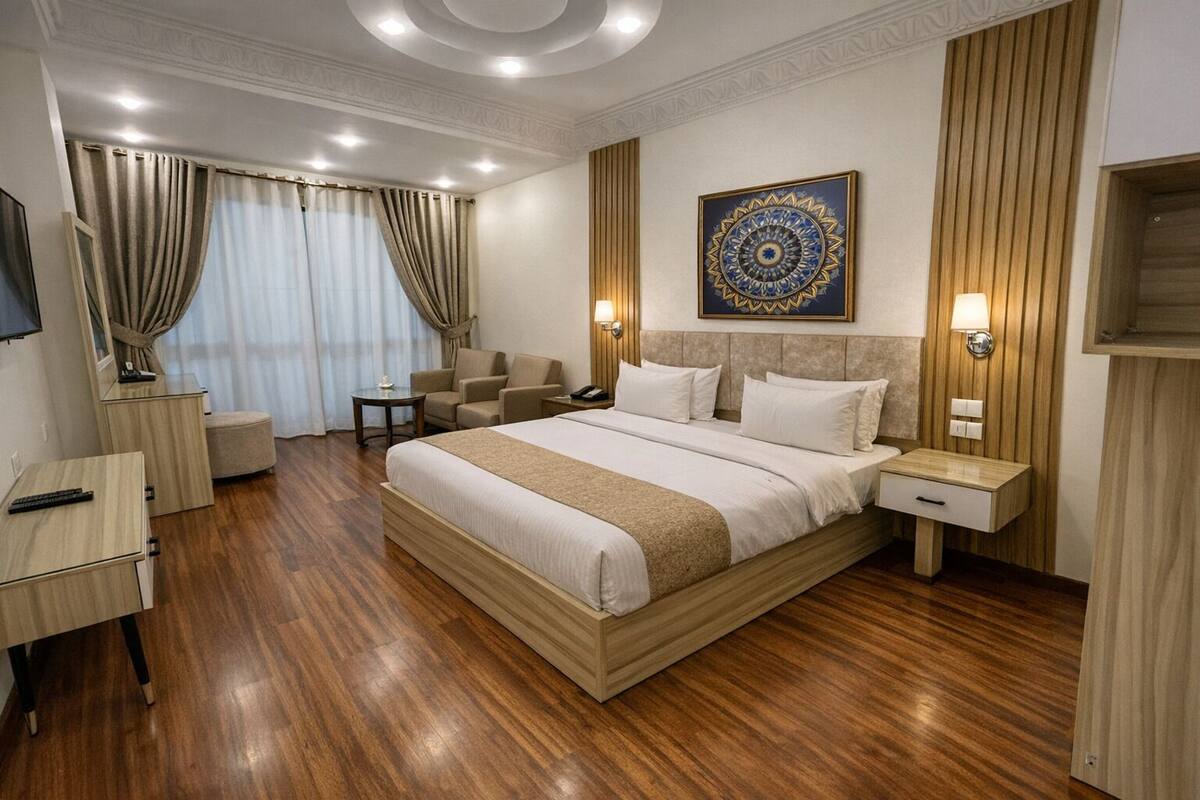 A hotel room with a large bed, a desk, a chair, and a television.