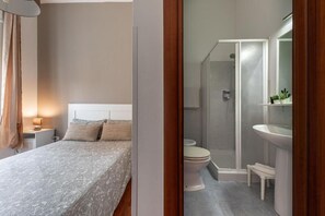 Un dormitorio con cama, mesita de noche y velador.
